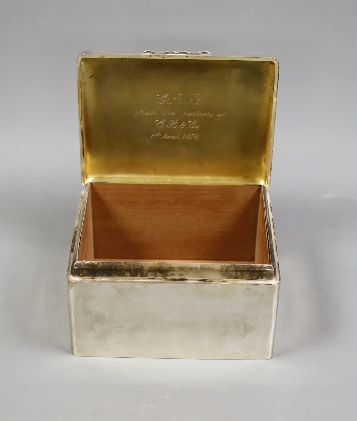 A George V silver mounted rectangular cigarette box, marks rubbed, maker's A & J Zimmerman, length 15.8cm.